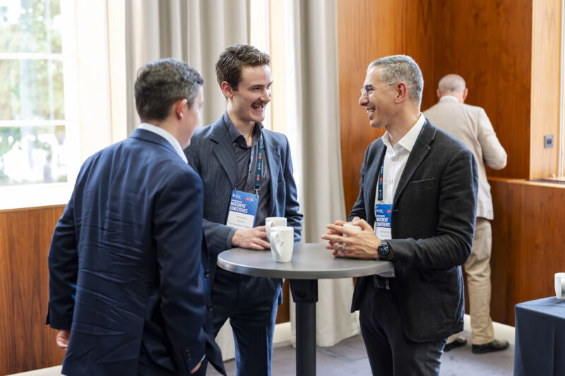 Three men talking at a conference table.