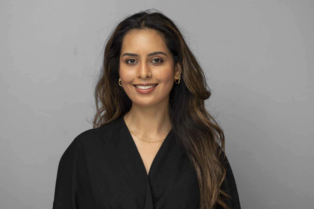 Person smiling in black dressed studio portrait.